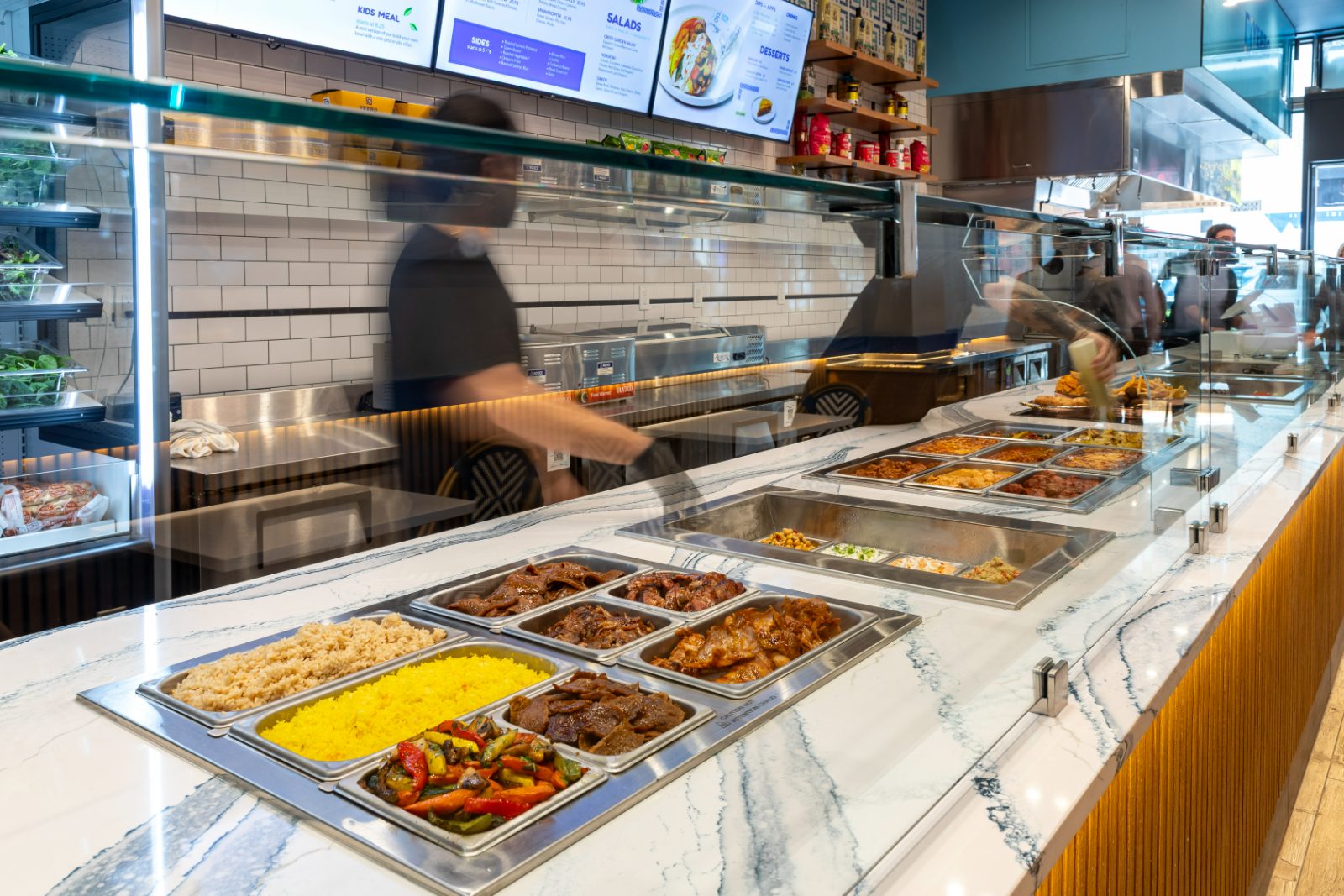 Hellenic Kitchen serving line with marble counter, fresh proteins, rices and roasted vegetables