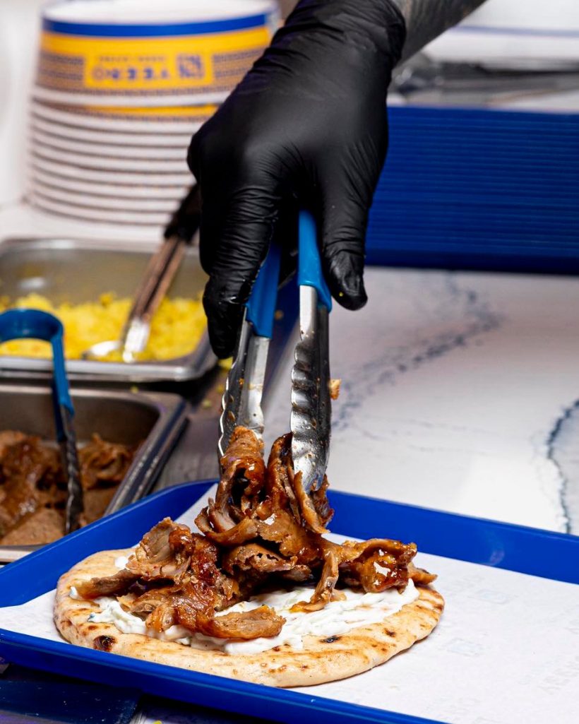 Spit-roasted yeero meat being piled onto warm pita